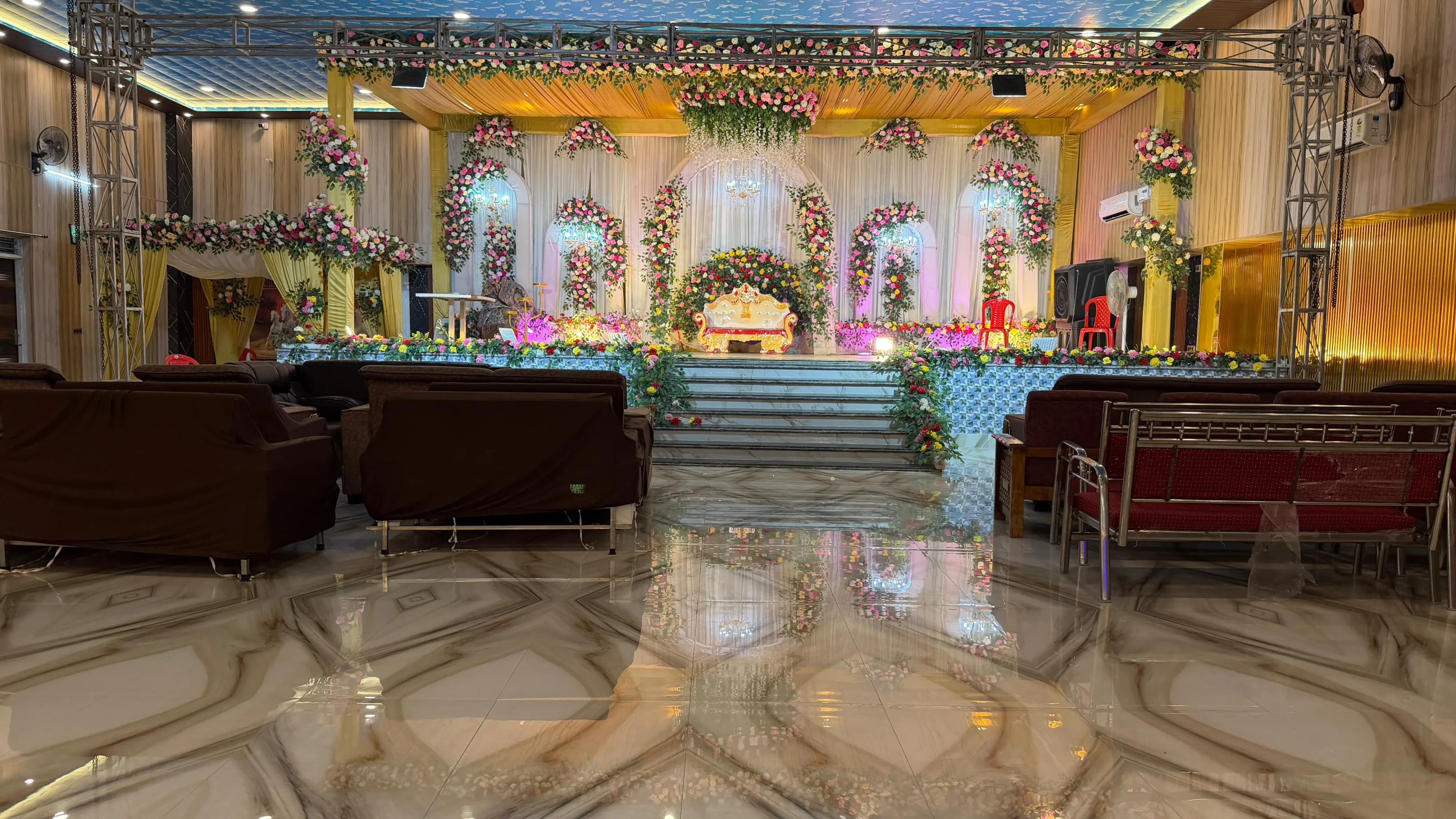 The reception stage framed by a floral arch, with lounge seating either side of the marble steps