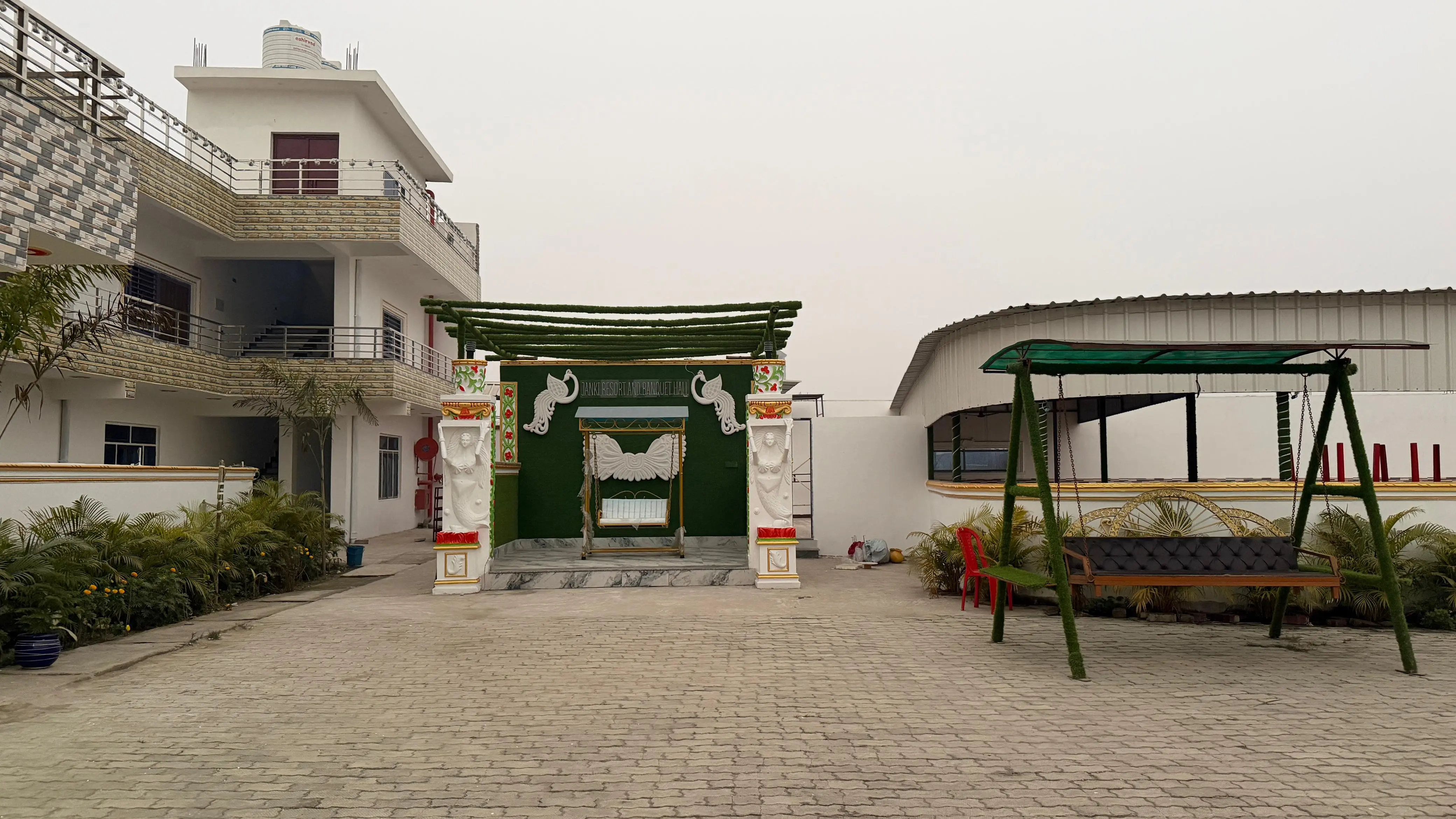 The decorated ceremonial gate in daylight, with a garden swing and the guest wing alongside